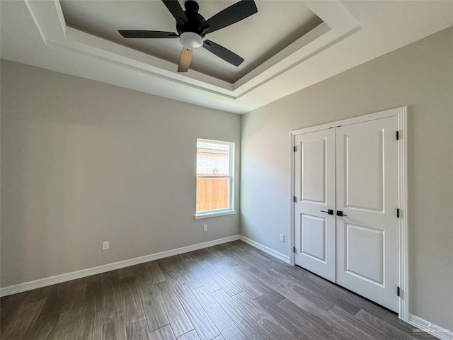 3807 Crimson St, Mission, TX 78574 - unfurnished bedroom with a tray ceiling, baseboards, dark wood-type flooring, a ceiling fan, and a closet