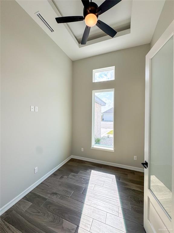 3807 Crimson St, Mission, TX 78574 - spare room featuring a raised ceiling, dark wood-style floors, a ceiling fan, and baseboards
