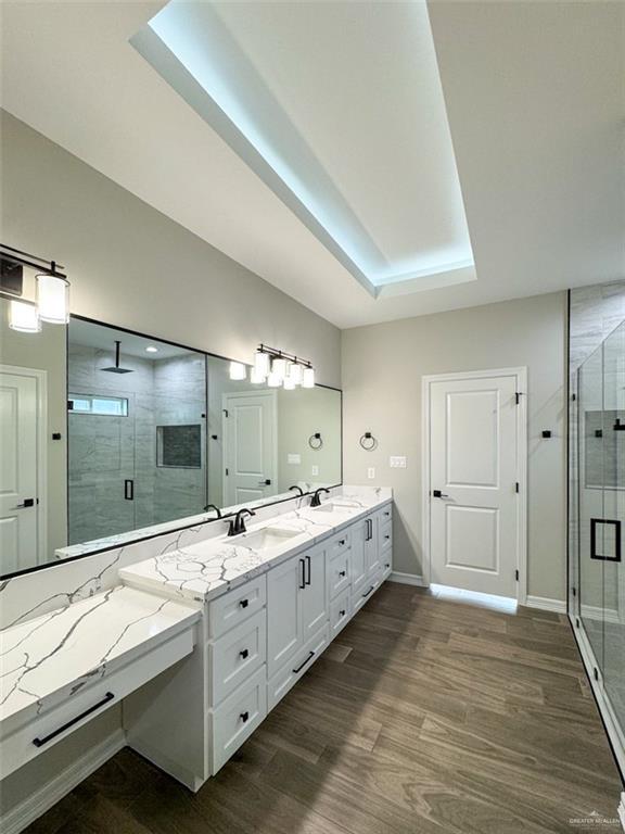3807 Crimson St, Mission, TX 78574 - bathroom featuring a shower stall, double vanity, a tray ceiling, and wood finished floors