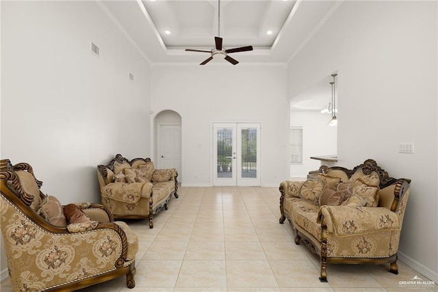 living area with french doors, ceiling fan, crown molding, a raised ceiling, and light tile patterned floors