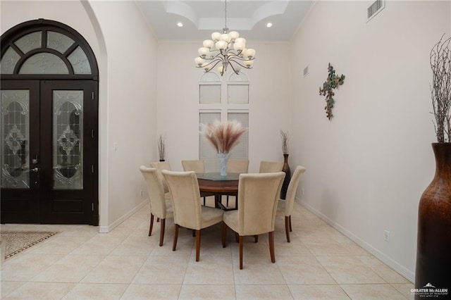 dining room with a raised ceiling, light tile patterned floors, an inviting chandelier, and french doors