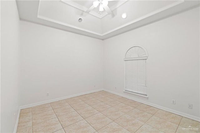 spare room with light tile patterned flooring, ceiling fan, and a raised ceiling