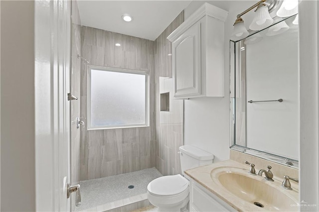 bathroom featuring tiled shower, vanity, and toilet