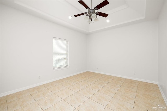 tiled spare room with ceiling fan and a raised ceiling