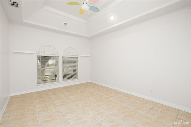 tiled spare room featuring ceiling fan and a raised ceiling