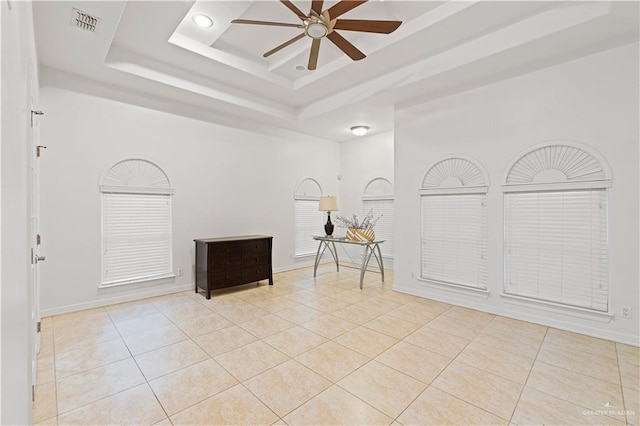 tiled spare room with a tray ceiling, a high ceiling, and ceiling fan