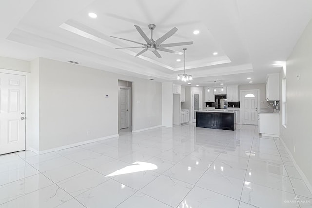 unfurnished living room featuring sink, a raised ceiling, and ceiling fan