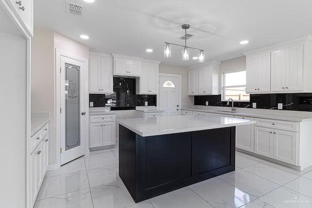 kitchen with sink, white cabinets, a center island, and pendant lighting