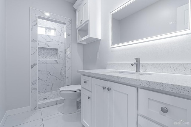 bathroom featuring toilet, a tile shower, and vanity