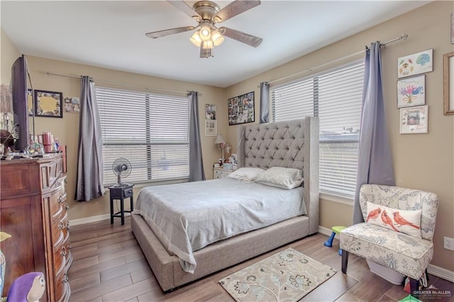 bedroom with multiple windows, baseboards, and wood finished floors