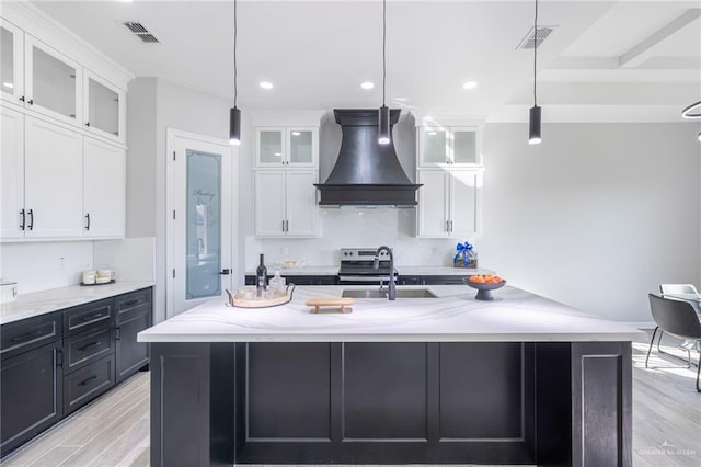 kitchen featuring white cabinetry, custom range hood, and hanging light fixtures