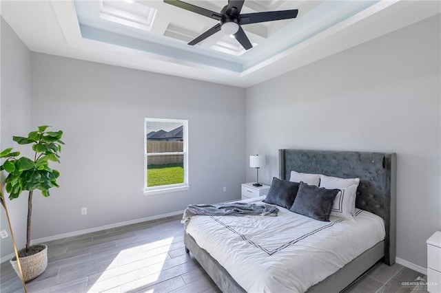 bedroom featuring ceiling fan, wood-type flooring, and a tray ceiling