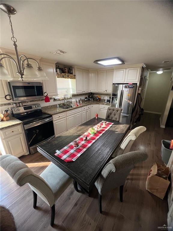 kitchen with sink, stainless steel appliances, dark hardwood / wood-style floors, decorative light fixtures, and white cabinets