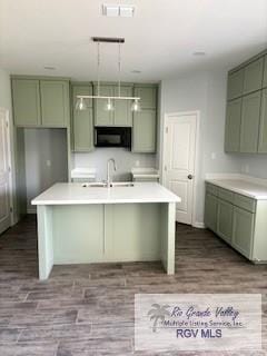 2906 Brushy Ct, Harlingen, TX 78552 - kitchen with green cabinetry, black microwave, a sink, and light countertops