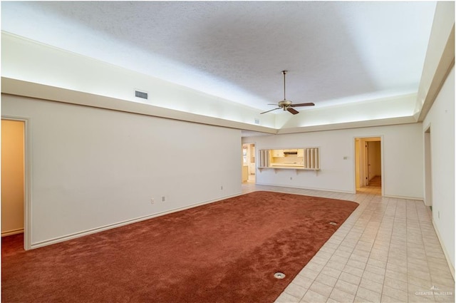 unfurnished living room featuring carpet flooring, a tray ceiling, and ceiling fan