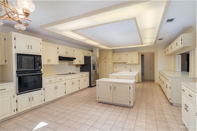 kitchen with black appliances, a raised ceiling, light tile patterned floors, decorative light fixtures, and a kitchen island