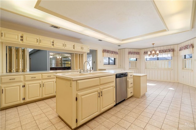 kitchen featuring a tray ceiling, cream cabinets, dishwasher, and an island with sink