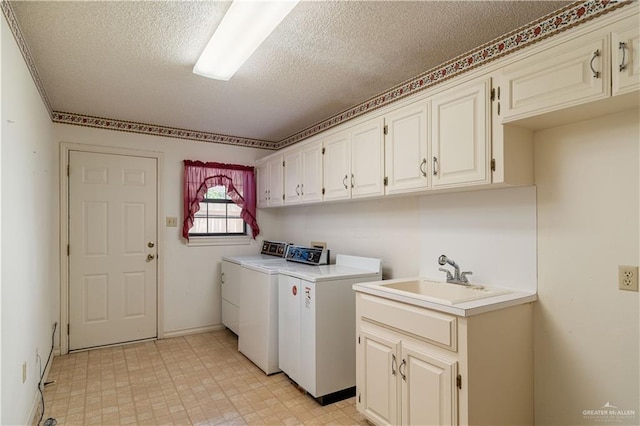 washroom featuring washer and dryer, a textured ceiling, cabinets, and sink