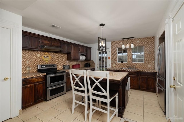 2113 W Harrison St, Weslaco, TX 78599 - kitchen with appliances with stainless steel finishes, a center island, decorative backsplash, dark brown cabinets, and light tile patterned floors