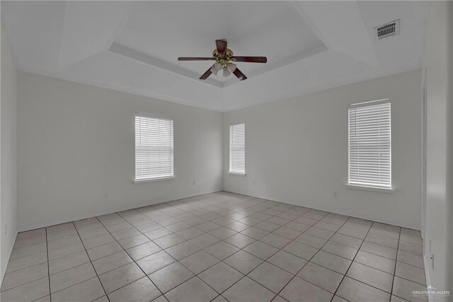 empty room featuring light tile patterned floors, a raised ceiling, and ceiling fan