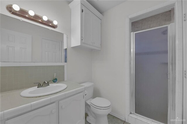 bathroom featuring tile patterned flooring, vanity, toilet, and a shower with shower door