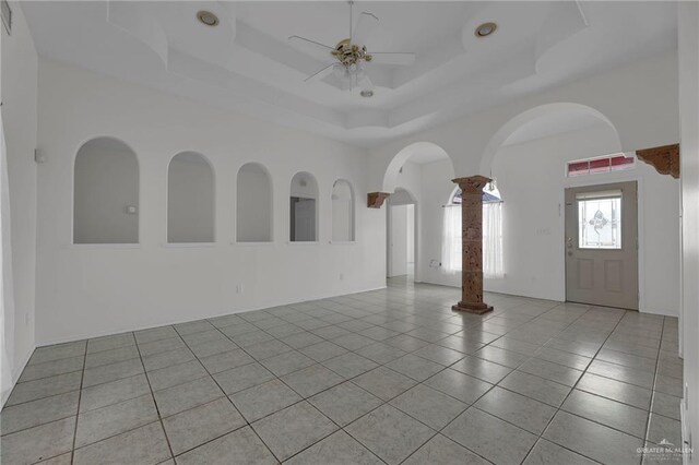 tiled spare room with ceiling fan and a raised ceiling