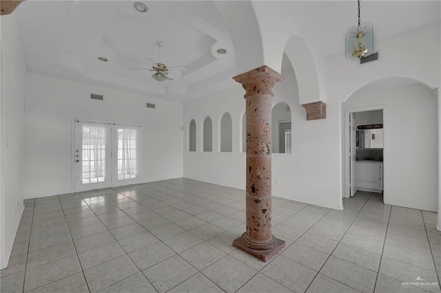 tiled empty room featuring a tray ceiling, ceiling fan, and french doors