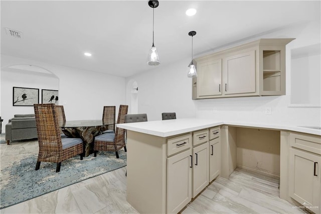 kitchen featuring kitchen peninsula, decorative light fixtures, and cream cabinetry