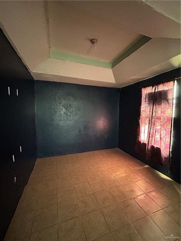 spare room featuring a tray ceiling and light tile patterned floors