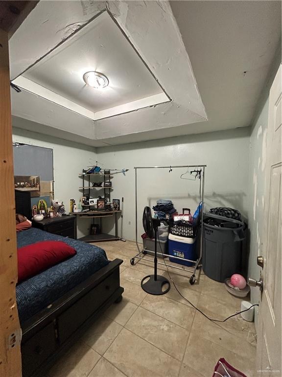 bedroom with a raised ceiling and light tile patterned floors