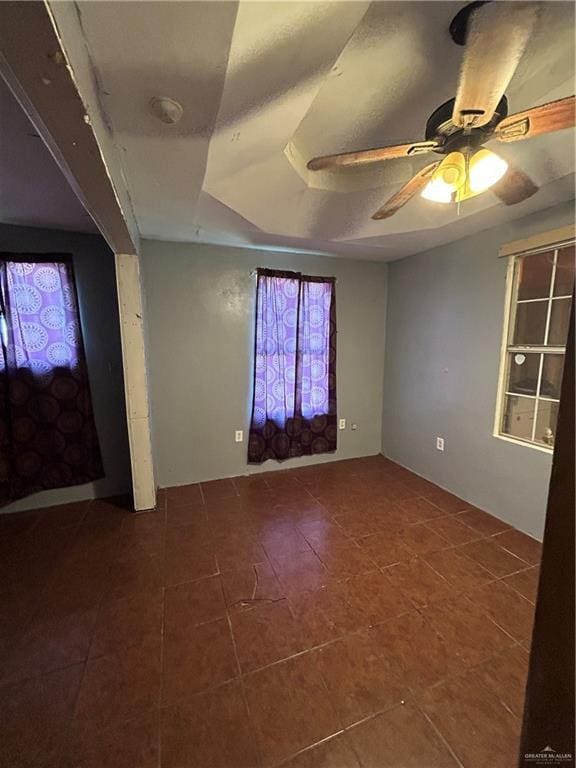 empty room featuring ceiling fan and a raised ceiling