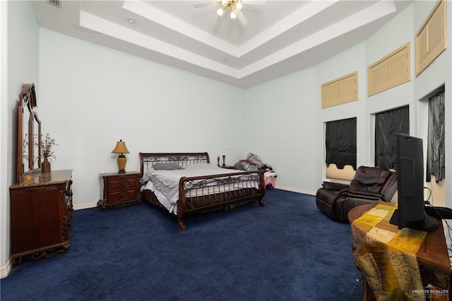 carpeted bedroom with a tray ceiling and ceiling fan