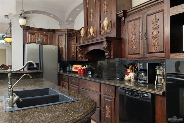 kitchen featuring dark stone counters, black appliances, sink, decorative light fixtures, and dark brown cabinets