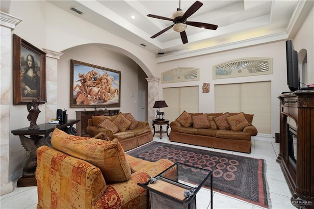 living room featuring ceiling fan, a raised ceiling, ornate columns, and light tile patterned floors