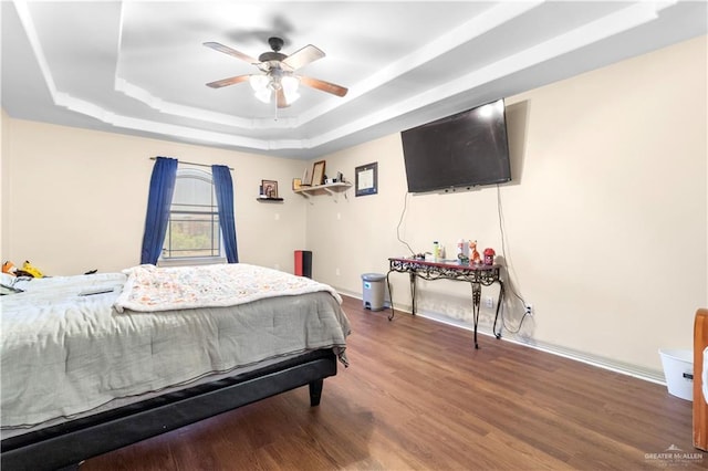 bedroom featuring ceiling fan, a raised ceiling, and wood-type flooring