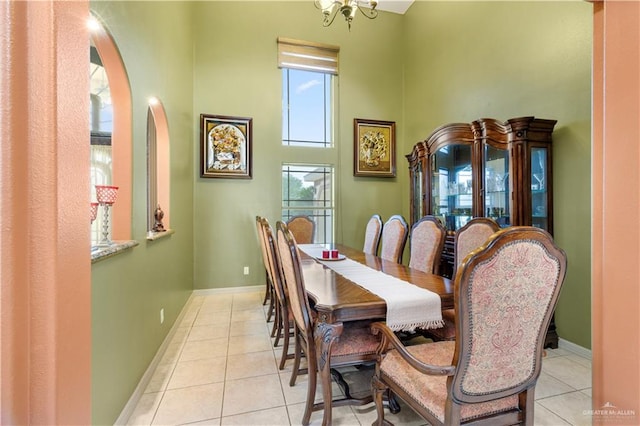 tiled dining room with a towering ceiling and a notable chandelier