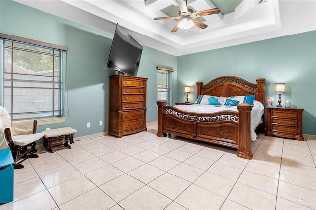 bedroom with ceiling fan, light tile patterned flooring, and a tray ceiling