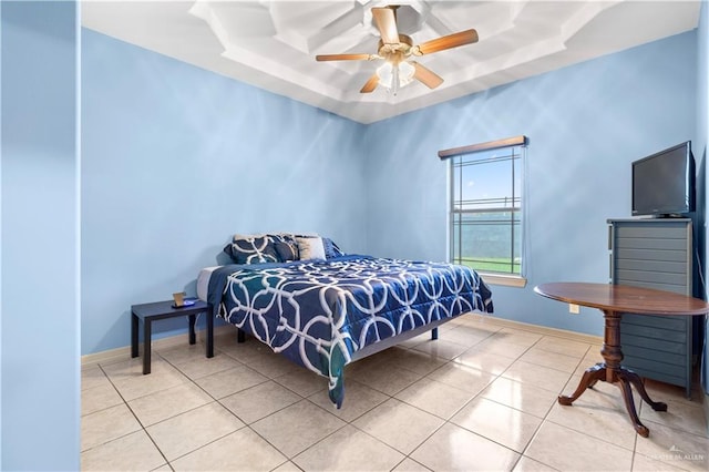 tiled bedroom featuring a raised ceiling and ceiling fan