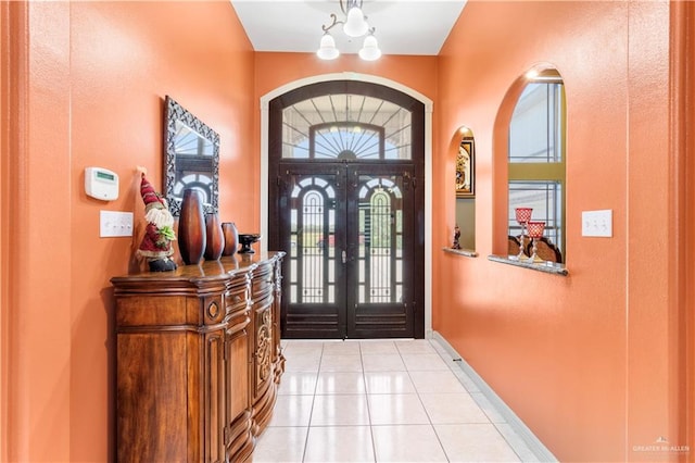 entrance foyer with a chandelier, french doors, and light tile patterned flooring