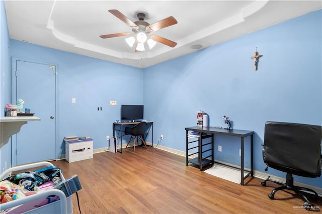 office space with hardwood / wood-style flooring, a raised ceiling, and ceiling fan