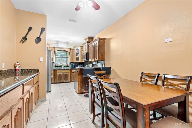 tiled dining room with ceiling fan and sink