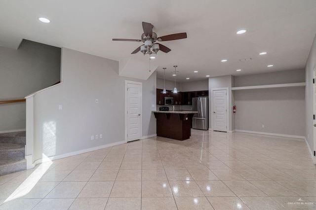 kitchen with ceiling fan, stainless steel appliances, a kitchen breakfast bar, kitchen peninsula, and light tile patterned flooring