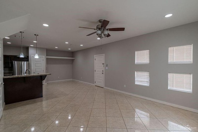 unfurnished living room featuring ceiling fan, sink, and light tile patterned floors