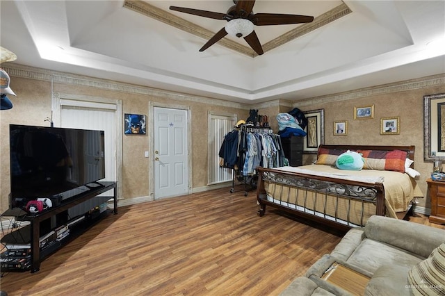 bedroom featuring hardwood / wood-style flooring, ceiling fan, and a tray ceiling