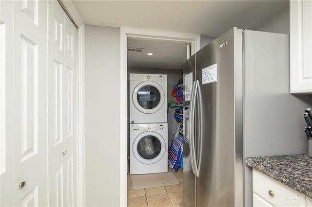 laundry area featuring stacked washing machine and dryer and light tile patterned flooring