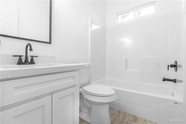 full bathroom with bathing tub / shower combination, hardwood / wood-style floors, vanity, and toilet