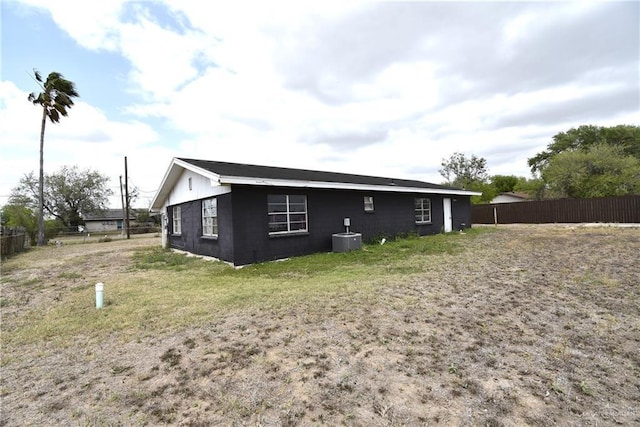 rear view of property with cooling unit, concrete block siding, and fence