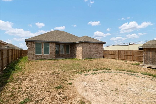 rear view of property with a fenced backyard, brick siding, and a yard