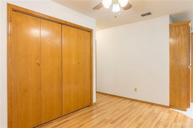unfurnished bedroom with light wood finished floors, baseboards, visible vents, a ceiling fan, and a closet