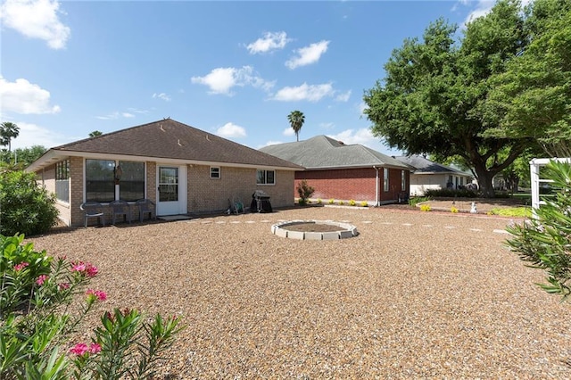 back of property with brick siding and a fire pit